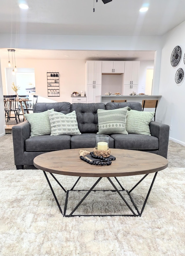 living area with light colored carpet, baseboards, and ceiling fan