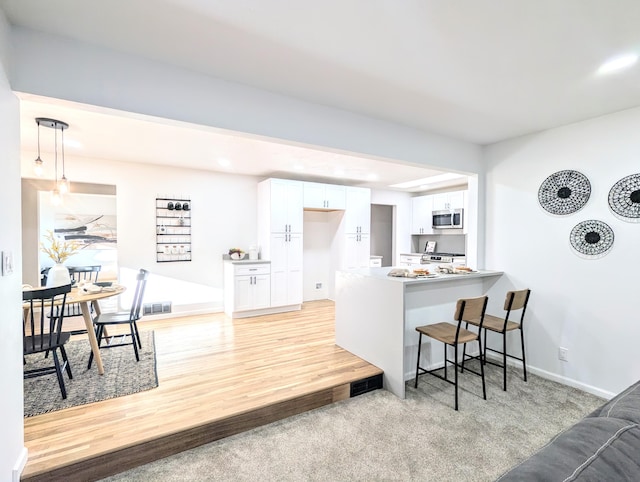 kitchen featuring visible vents, a peninsula, a breakfast bar area, appliances with stainless steel finishes, and white cabinets