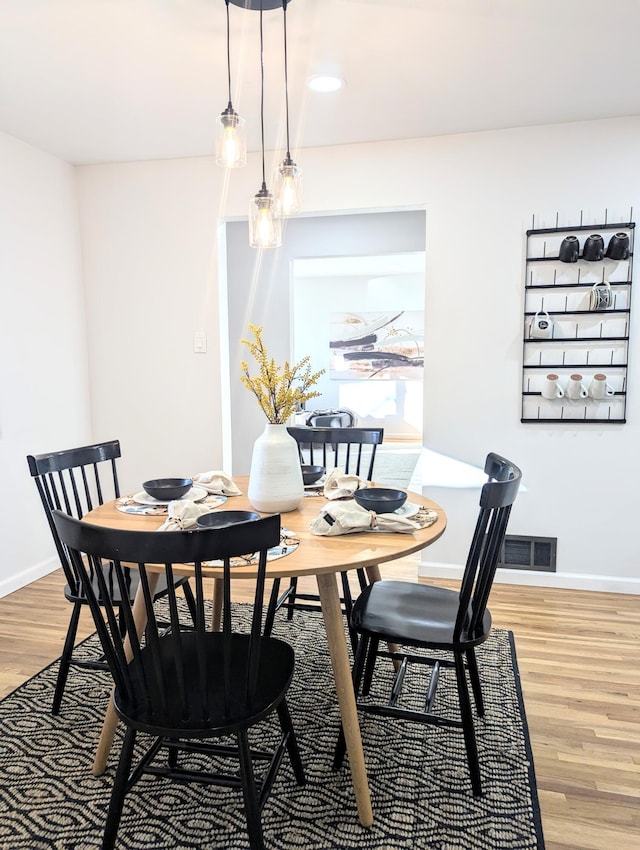 dining area with light wood finished floors, visible vents, and baseboards