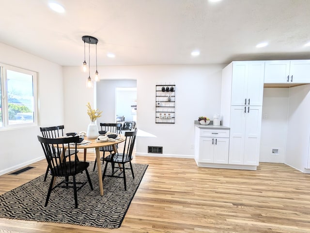 dining space with light wood-style floors, visible vents, and baseboards