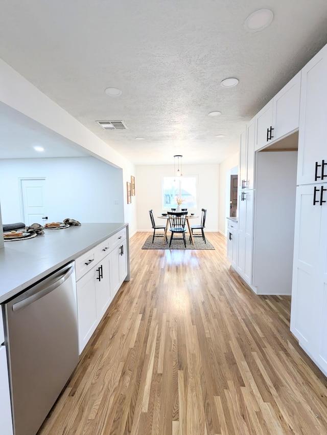 kitchen featuring stainless steel dishwasher, light wood-style flooring, light countertops, and white cabinetry