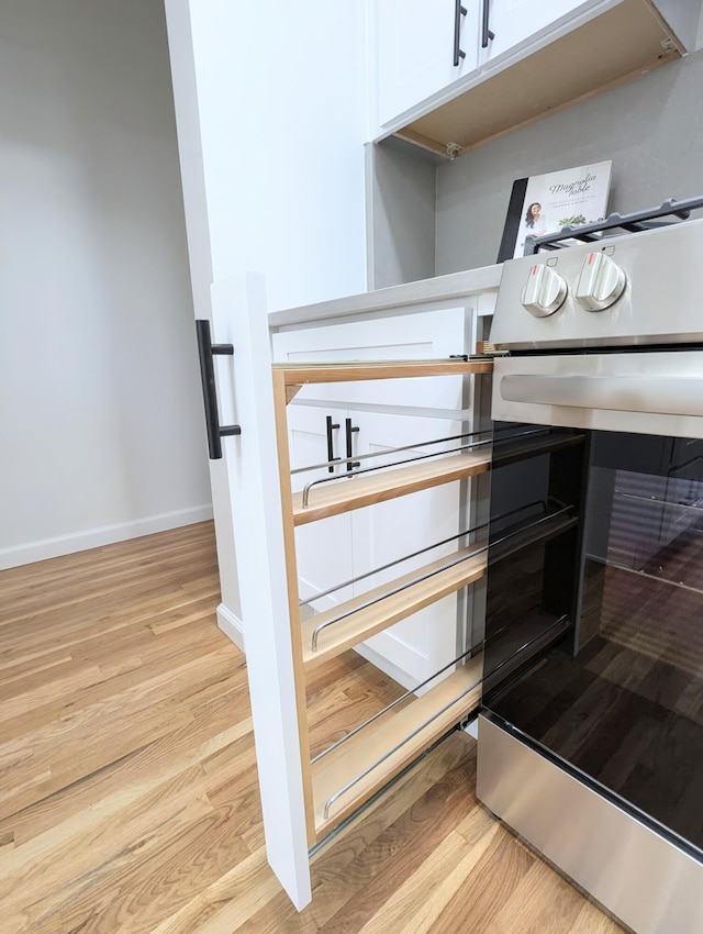 interior details with baseboards, wine cooler, white cabinetry, and light wood finished floors