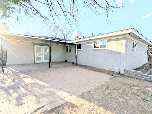 back of property with a patio, central air condition unit, french doors, and brick siding