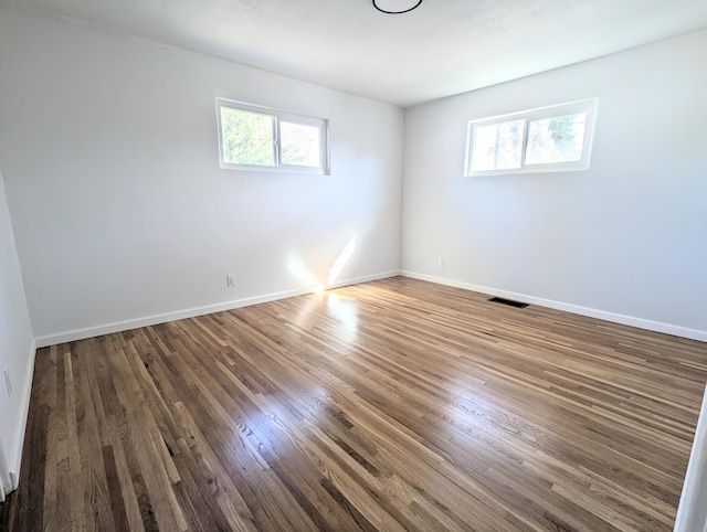 unfurnished room with visible vents, baseboards, and wood finished floors