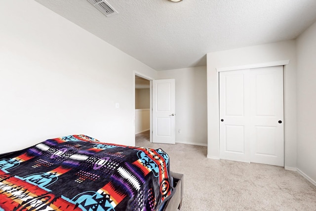 bedroom featuring visible vents, light colored carpet, a textured ceiling, and baseboards