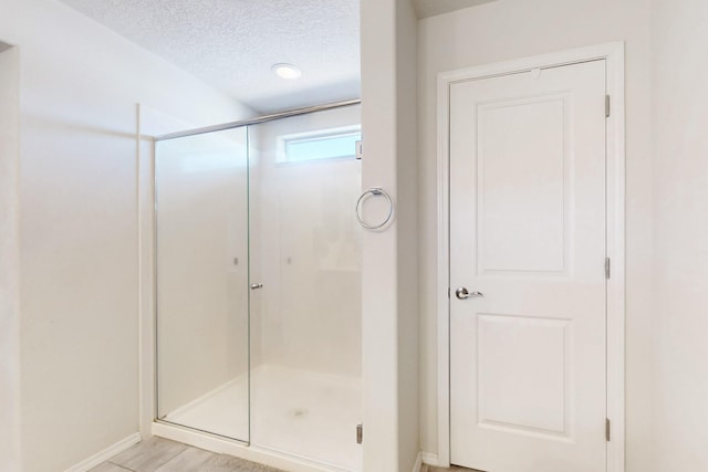 full bathroom with a shower stall and a textured ceiling