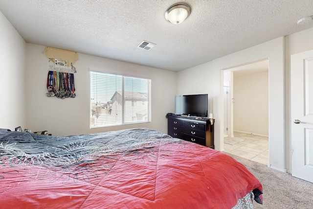 bedroom featuring visible vents, light carpet, and a textured ceiling