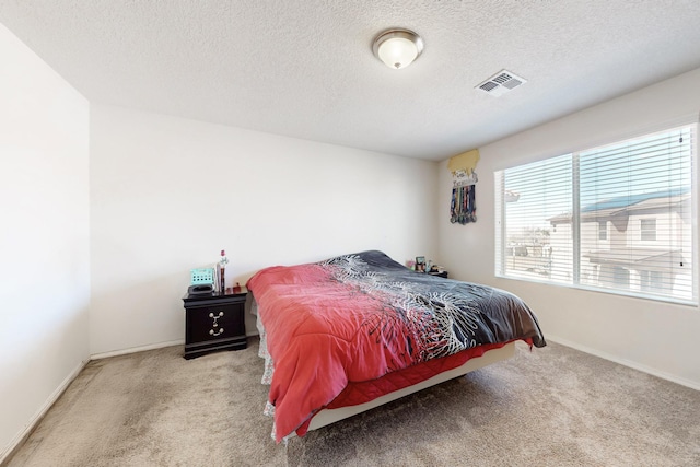 bedroom with a textured ceiling, carpet, visible vents, and baseboards