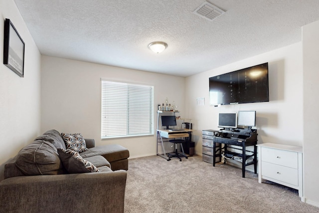 carpeted office space with visible vents, a textured ceiling, and baseboards