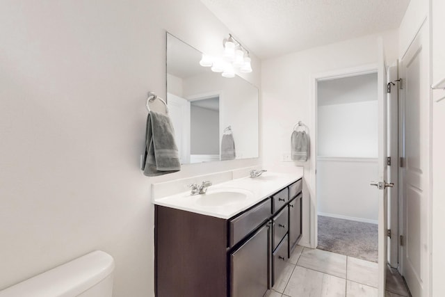 bathroom featuring a sink, toilet, double vanity, and a textured ceiling