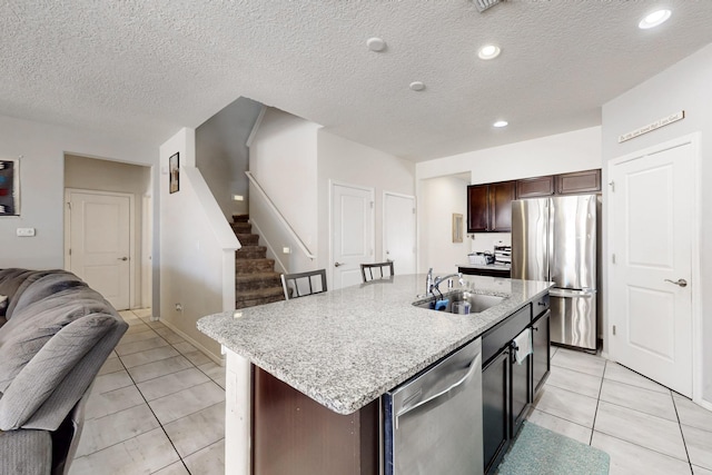 kitchen featuring light tile patterned flooring, open floor plan, appliances with stainless steel finishes, and a sink