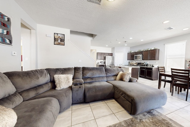 living room featuring light tile patterned floors, recessed lighting, visible vents, and a textured ceiling