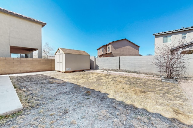 view of yard featuring a fenced backyard, a storage unit, and an outdoor structure