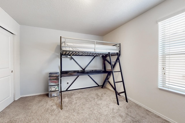 bedroom with carpet, baseboards, and a textured ceiling