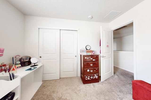 bedroom with light carpet, visible vents, a textured ceiling, and a closet