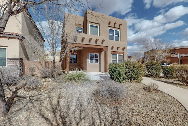 pueblo-style house with fence and stucco siding