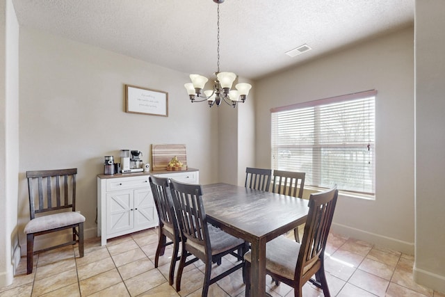 dining space with a chandelier, a textured ceiling, light tile patterned flooring, visible vents, and baseboards