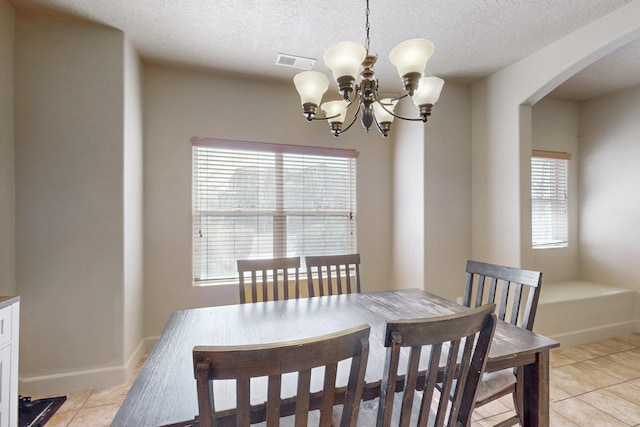 dining space with light tile patterned floors, visible vents, arched walkways, an inviting chandelier, and a textured ceiling