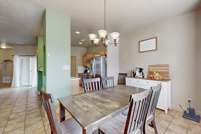 dining space with light tile patterned floors, arched walkways, visible vents, baseboards, and an inviting chandelier