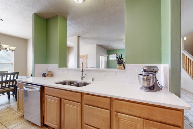 kitchen featuring a wealth of natural light, light countertops, a sink, and dishwasher