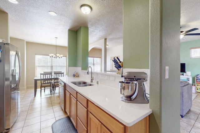 kitchen with light tile patterned floors, stainless steel appliances, light countertops, decorative backsplash, and a sink