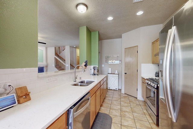 kitchen with light tile patterned floors, a sink, light countertops, appliances with stainless steel finishes, and backsplash