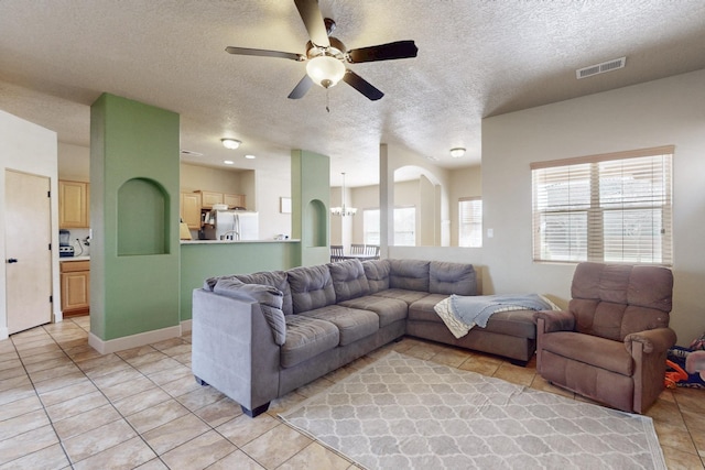 living area with arched walkways, visible vents, light tile patterned flooring, a textured ceiling, and ceiling fan with notable chandelier