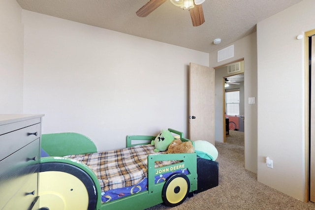 carpeted bedroom featuring a textured ceiling, visible vents, and a ceiling fan