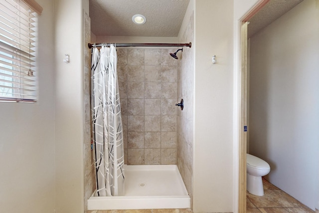 bathroom with a stall shower, a textured ceiling, and toilet