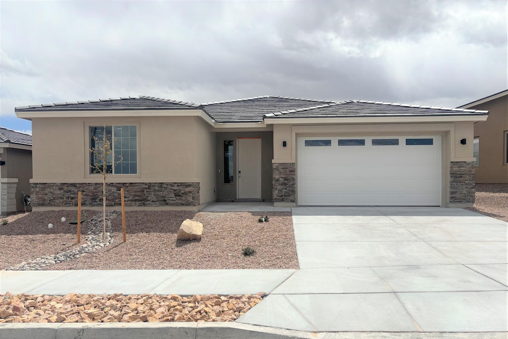 view of front of property with stone siding, an attached garage, and driveway