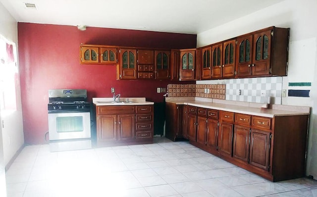 kitchen with light countertops, visible vents, decorative backsplash, glass insert cabinets, and stainless steel gas stove