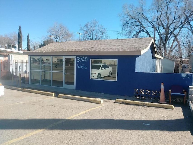 exterior space with uncovered parking and a shingled roof