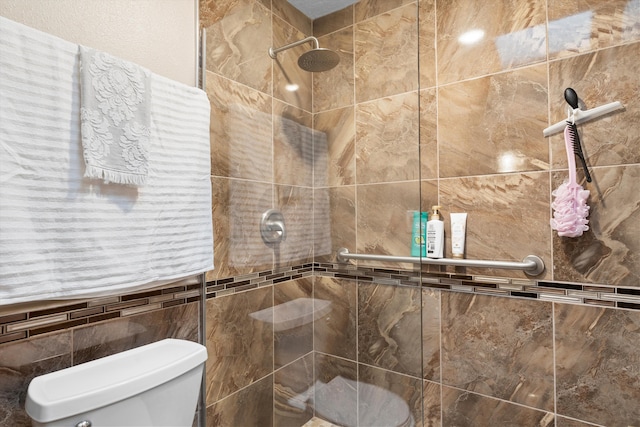 full bathroom with a tile shower and toilet