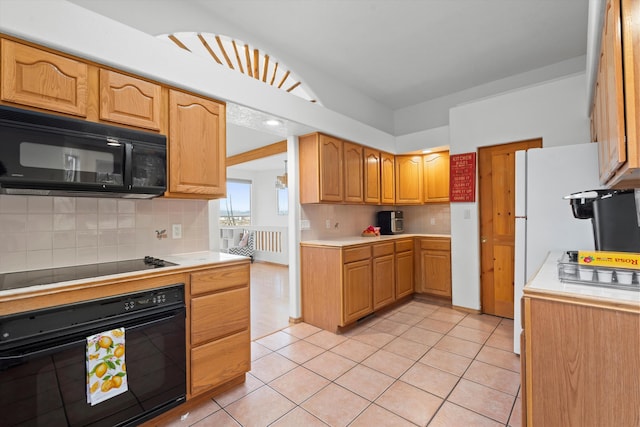 kitchen with black appliances, tasteful backsplash, light tile patterned floors, and light countertops