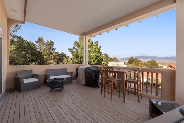 wooden deck with a grill, a mountain view, and an outdoor living space with a fire pit