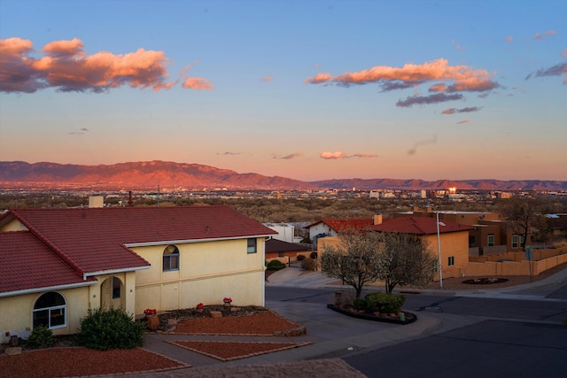 exterior space featuring driveway, a tiled roof, a mountain view, and stucco siding