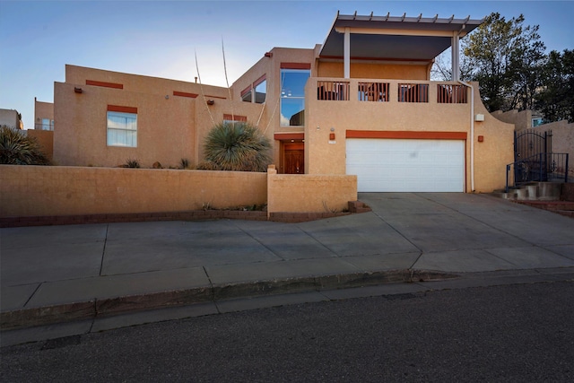 pueblo-style home with driveway, a garage, a gate, and stucco siding