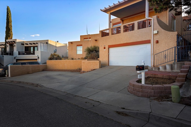 view of front facade with a garage, a balcony, concrete driveway, and stucco siding