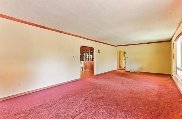 627 Fairway Rd NW, Albuquerque, NM 87107 - empty room with arched walkways, carpet floors, ornamental molding, and a textured ceiling