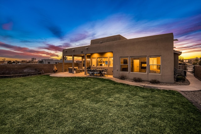 back of property with stucco siding, a patio area, a yard, and fence