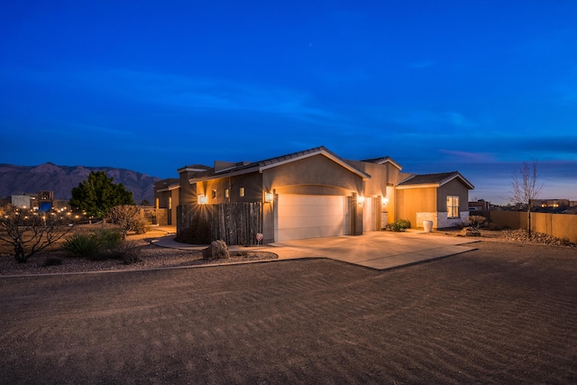 single story home with stucco siding, concrete driveway, a mountain view, fence, and a garage