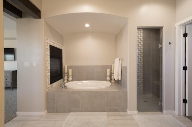 bathroom featuring a stall shower, baseboards, and a bath