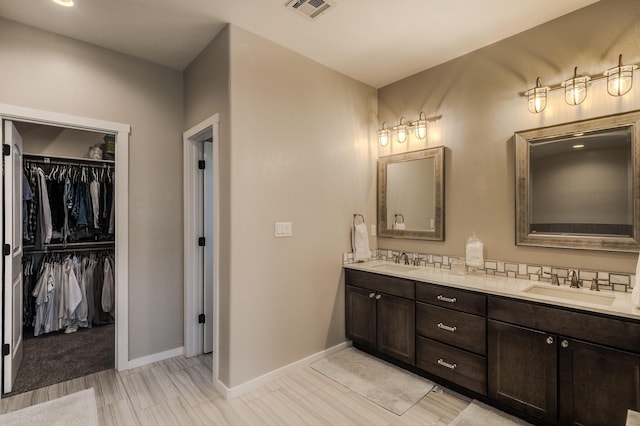 bathroom featuring double vanity, a spacious closet, a sink, and visible vents