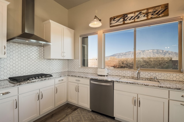 kitchen with tasteful backsplash, stainless steel appliances, wall chimney range hood, a mountain view, and a sink