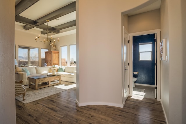 hall with a chandelier, dark wood-style flooring, beam ceiling, and baseboards