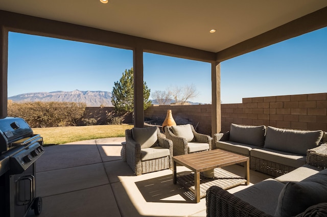 view of patio featuring a fenced backyard, a grill, an outdoor living space, and a mountain view