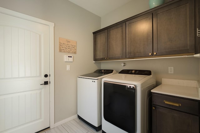 laundry area featuring cabinet space, baseboards, and separate washer and dryer