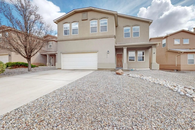 traditional-style home with stucco siding, a garage, and driveway