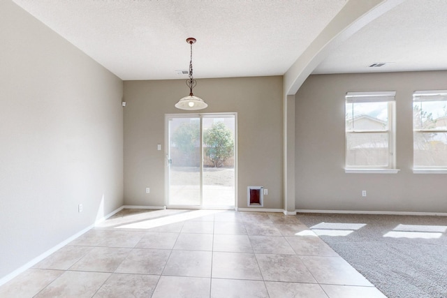 unfurnished room featuring light tile patterned flooring, baseboards, arched walkways, and a textured ceiling