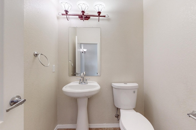 bathroom with baseboards and toilet